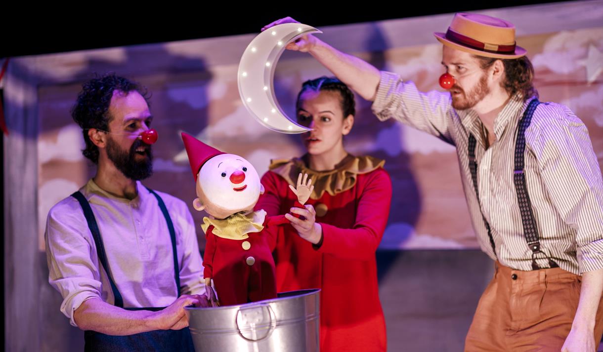 Actors dressed as clowns interacting with a clown puppet