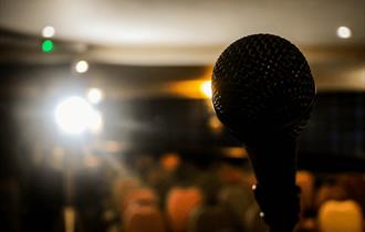 Open Mic - a microphone illuminated by a spotlight