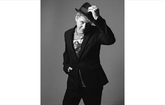Dom Pipkin, black and white, raising his hat