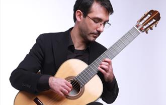 Daniele Piroddi - posing seated whilst playing acoustic guitar