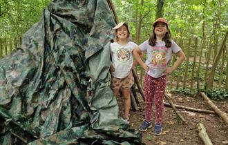 Two small girls in the woods building a den