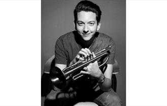 Freddie Gavita, black and white photo holding a trumpet
