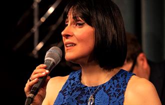 Georgia Mancio singing in a blue dress © Tatiana Gorilovksy