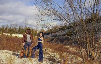 Hannah Sanders & Ben Savage 2025 - posed in nature with a guitar