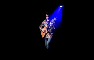 Nicolas Meier playing guitar under a blue spotlight ©Eric Humair
