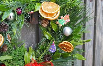 Christmas wreath with fir cones, baubles, gingerbread person and dried orange