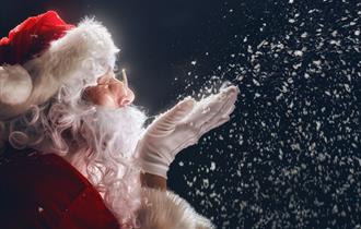 Father Christmas blowing snowflakes from his hand