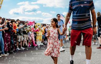TOTfest | girl carrying ice cream and walking hand in hand through bubbles