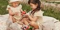 Children sitting on picnic blanket wearing Newbie childrenswear