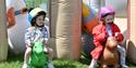 Two young girls dressed as jockeys racing on bouncing inflatable horses