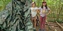 Two small girls in the woods building a den