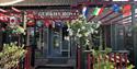 A vibrant restaurant facade with flags draped from the awning, contributing to a lively dining environment.