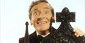 Kenneth Williams behind a wooden chair