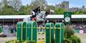 Royal Windsor Horse Show - showjumper clearing a large fence with Windsor Castle in the background