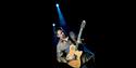 Nicolas Meier playing guitar under a blue spotlight ©Eric Humair
