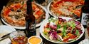 A selection of pizzas, beer, and dips