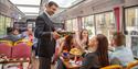 Person pouring a glass of prosecco for a passenger on Golden Tours Royal Windsor Afternoon Tea Bus Tour