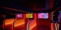 Dark, futuristic interactive exhibit with glowing red-orange counters, illuminated panels, and colorful screens in a dramatic, immersive space.
