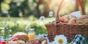 Picnic basket with bread and strawberries in a meadow with daisies
