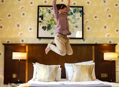 child jumping on bed