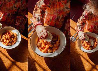 Child sprinkling parmesan on pasta