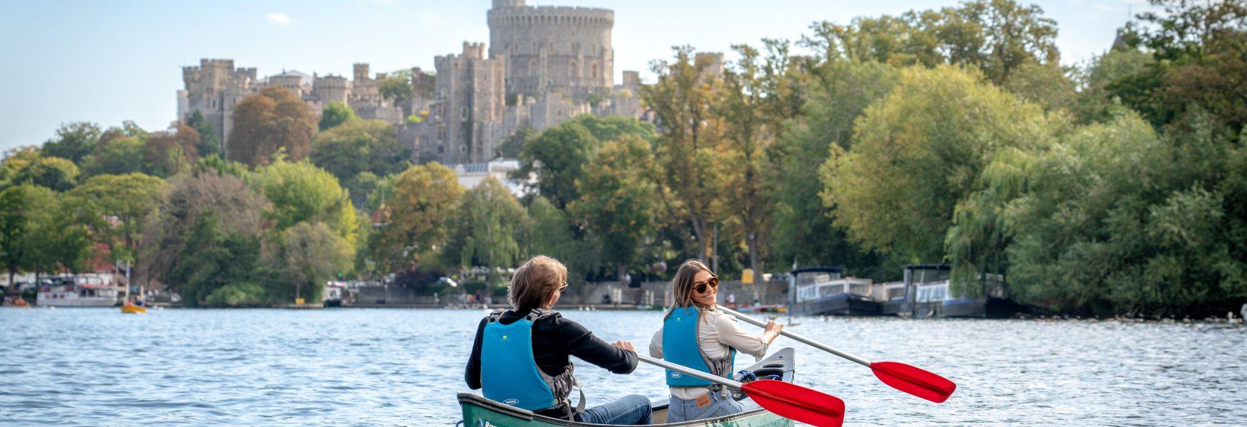 Couple canoeing on the River Thames with Windsor Castle in the distance