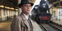 Scene from One Life, man stood on railway station platform by steam train