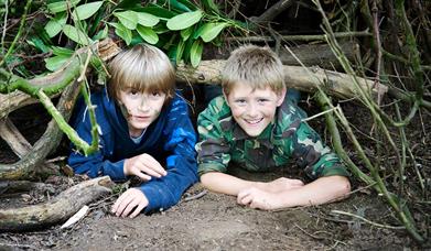 An image of children in their woodland den. Photograph by Discovery Photography