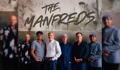 image of the band the manfreds. 6 men are all looking at the camera in front of a wall.