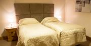 An image of inside a bedroom with two single beds.