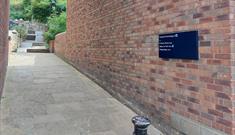An image of Caedmon's Trod flagged pathway entrance with walled mounted sign.