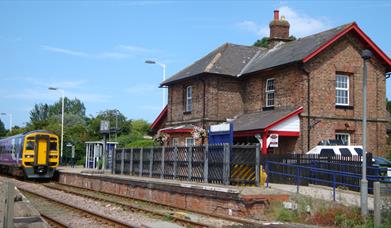 An image of outside The Old Waiting Rooms with a train passing by