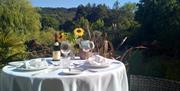 An image of outside Courtyard Restaurant silver service table setting with a garden view.