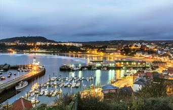An image of Scarborough Harbour with street lights lit up
