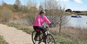 An image of woman cycling next to lake