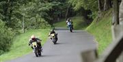 An image of 3 motorbikes riding down a road.