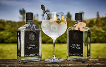 An image of two dry gin bottles between a poured gin glass at Raisthorpe Manor Fine Foods