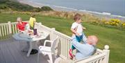An image of a family on the deck enjoying the sun at Reighton Sands Holiday Park
