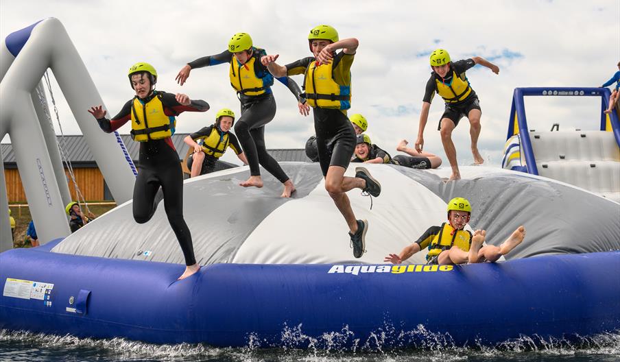 An image of Scarborough College students jumping off the inflatable AquaPark