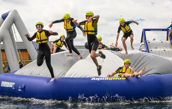 An image of Scarborough College students jumping off the inflatable AquaPark