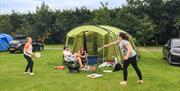 An image of a family playing outside their tent at Robin Hood Caravan Park